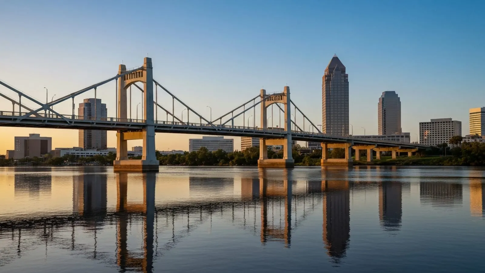 Editorial photograph of the Main Street Bridge over the St. Johns River in Jacksonville at golden hour with the downtown Jacksonville skyline visible behind it.