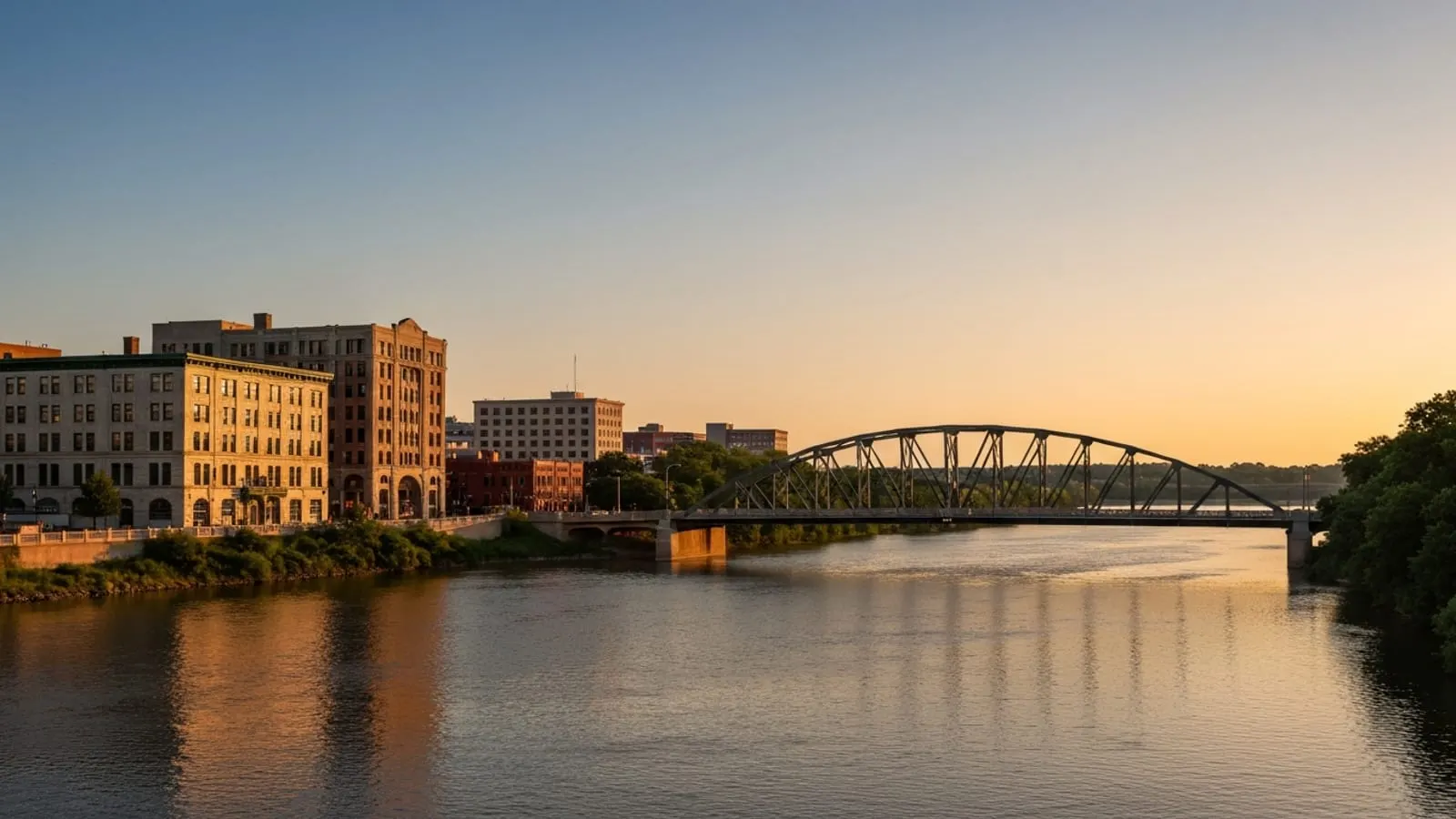 Editorial photograph of the Illinois River bluffs at Peoria Illinois at golden hour with the Murray Baker Bridge crossing the river and downtown Peoria limestone and brick buildings on the western bank.