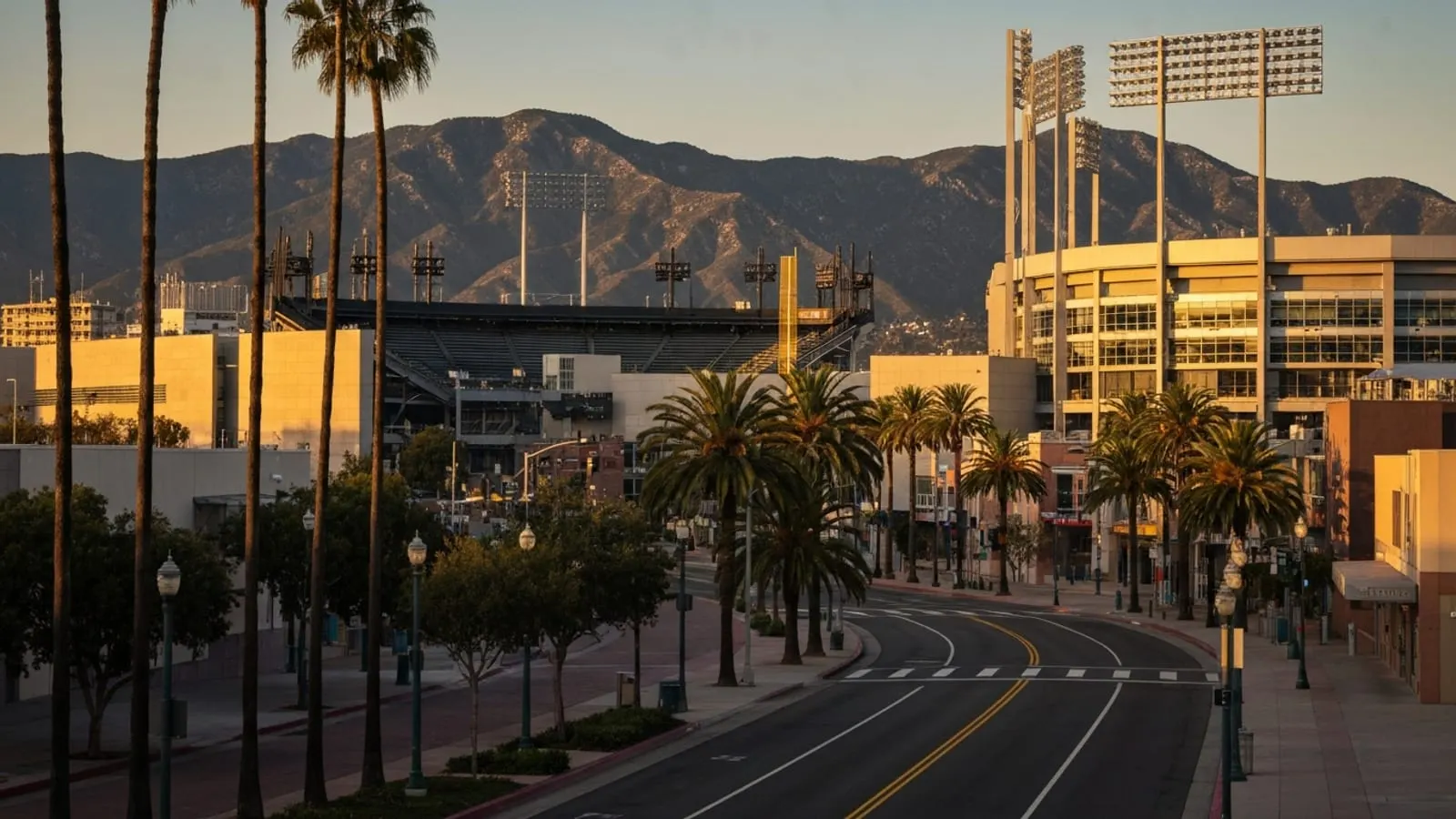 Editorial photograph of the Honda Center and Angel Stadium area in Anaheim at golden hour with the Santa Ana Mountains visible in the background.