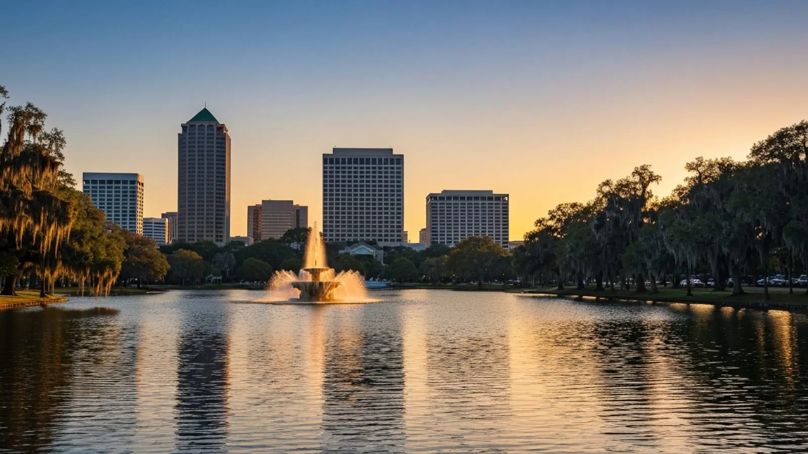 Editorial photograph of Lake Eola in downtown Orlando at golden hour with the iconic fountain in the middle of the lake and the downtown Orlando skyline behind it.