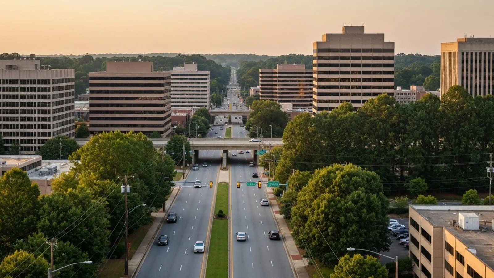 Editorial photograph of the Roswell Road corridor in Sandy Springs Georgia at golden hour with mid-rise office buildings and tree-lined boulevards.