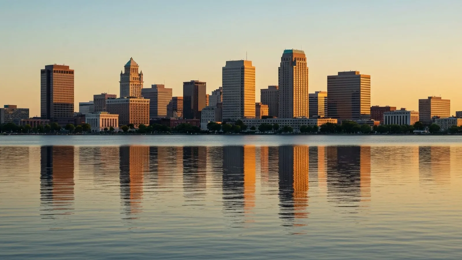 Editorial photograph of the downtown Syracuse skyline at golden hour viewed from the Onondaga Lake shoreline.