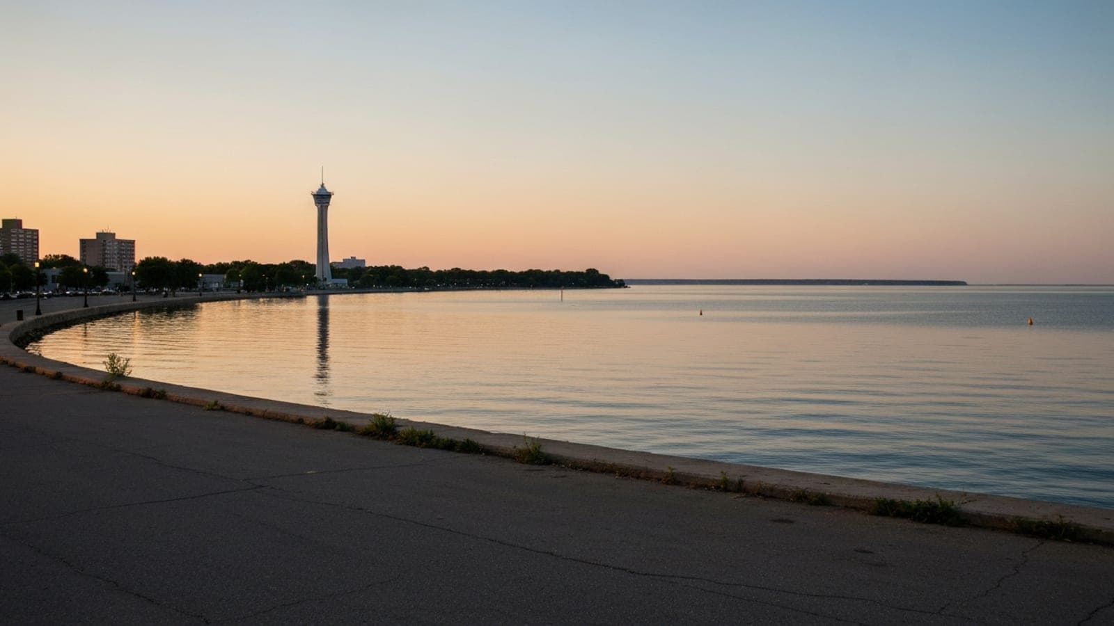 Editorial photograph of Presque Isle State Park and the Erie bayfront skyline at golden hour with Lake Erie stretching to the horizon and the Bicentennial Tower visible.