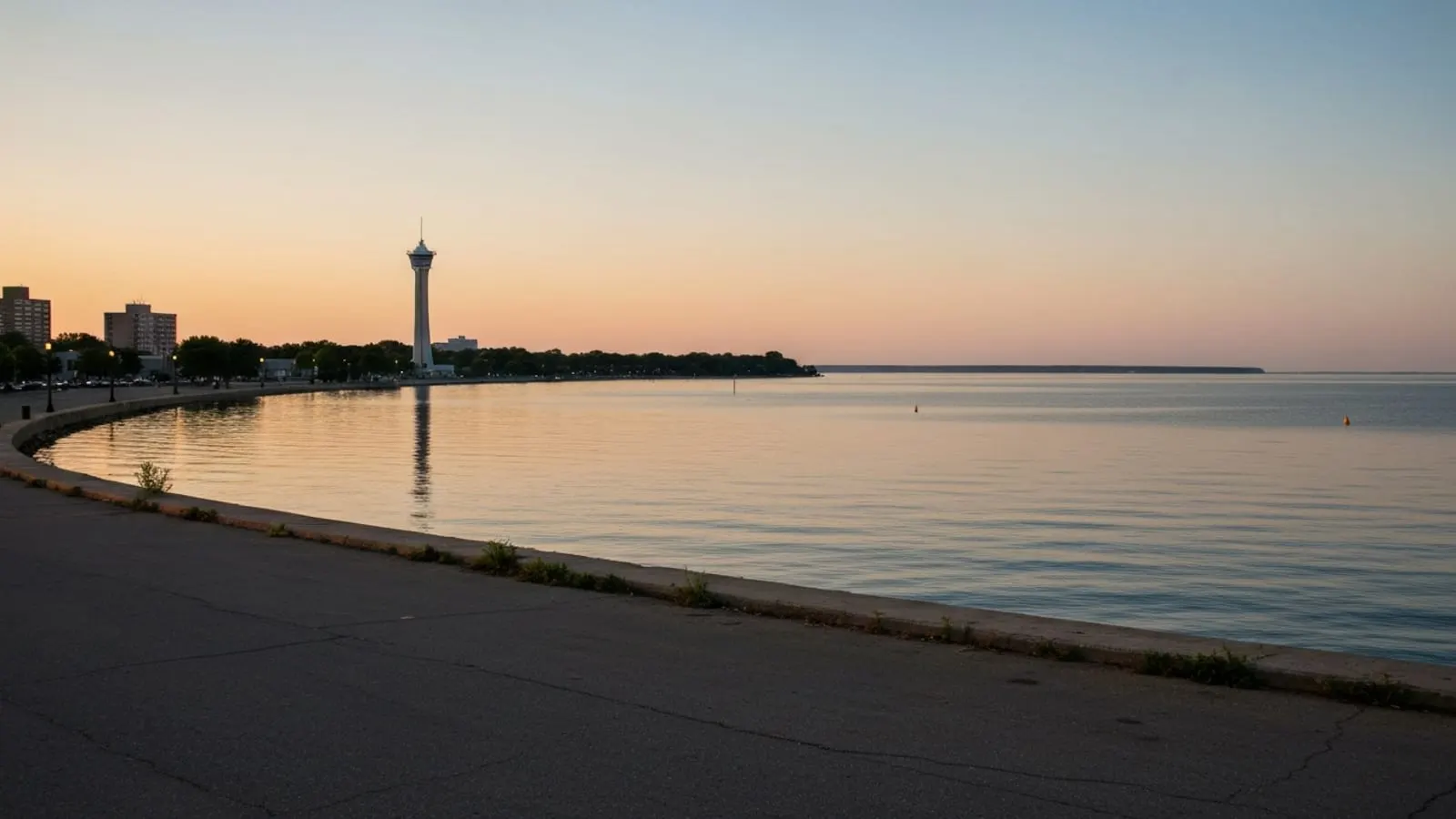 Editorial photograph of Presque Isle State Park and the Erie bayfront skyline at golden hour with Lake Erie stretching to the horizon and the Bicentennial Tower visible.